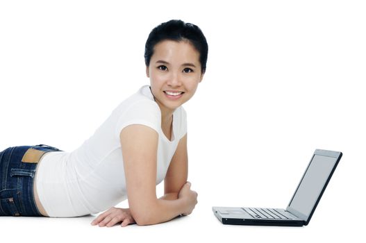 Attractive young Asian woman lying on floor with laptop over white background.