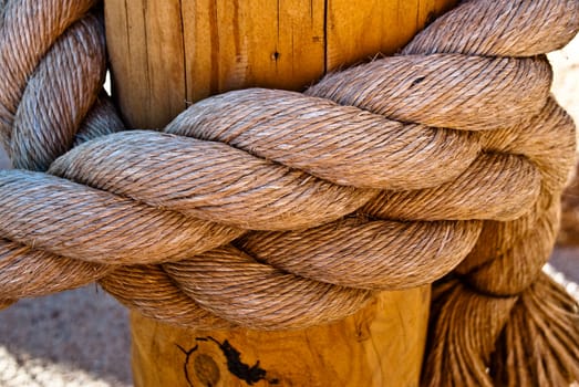 Large nautical rope tied on wooden post