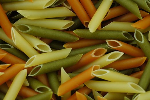 uncooked spaghetti tubes colored background of macro