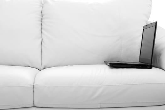 A black laptop computer on white sofa