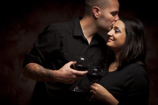 Happy Mixed Race Couple Flirting and Holding Wine Glasses on a Dark Background.