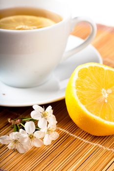 Tea in white cup with lemon and cherry flower