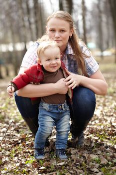 Beautiful young mother embracing her one year sonny in the park. This shot was made in the first day of spring.