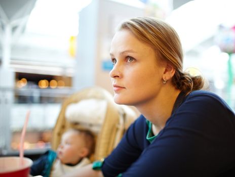 Portrait of a beautiful a bit tired girl having rest in the supermarket. Shallow dof, nice warm colors, natural sunlight through the windows.