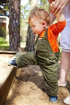 The first steps of the kid. Outdoors.