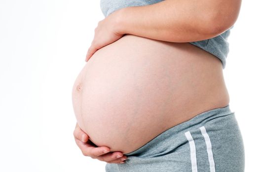 Pregnant woman holding belly against white background.