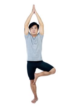 Portrait of a young Asian man practicing yoga over white background.