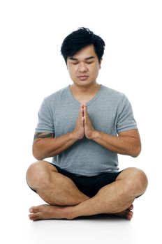 Portrait of a handsome Asian man doing meditation on white background.