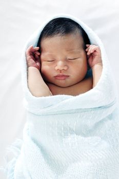 Portrait of a newborn baby sleeping peacefully, wrapped in blanket.