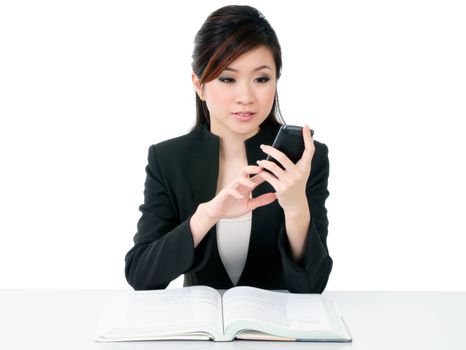 Portrait of an attractive young businesswoman text messaging on her cellphone over white background.