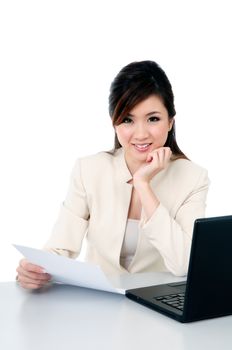 Portrait of a happy young Asian businesswoman at office desk, over white background.