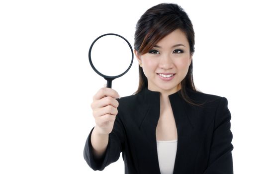 Portrait of a beautiful young businesswoman holding and looking at magnifying glass, over white background.