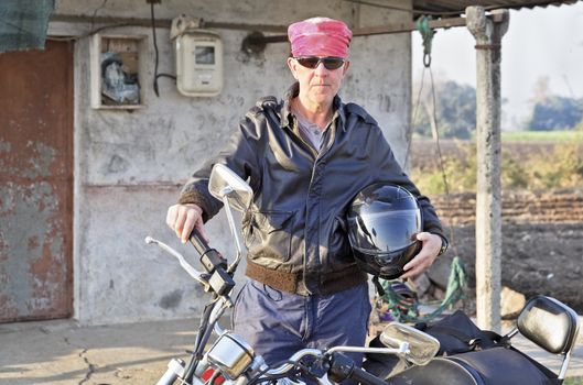 Caucasian motor cyclist touring India outs a shack in Gujarat hinterlands