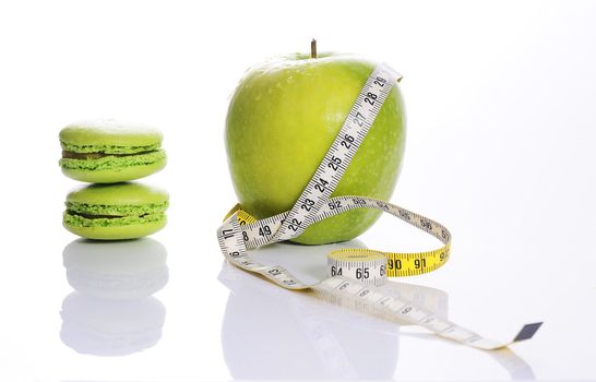 Apple, macarons and measuring tape. Concept of nutrition