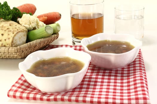 Beef consomme with root vegetables with a glass of juice and water