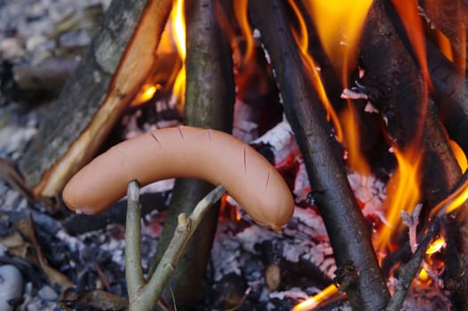 a sausage grilled on a camp fire