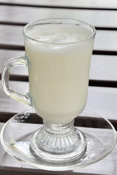 Hot milk in clear glass on wooden table
