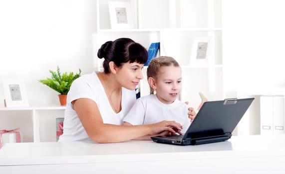 Mom and daughter are working together for a laptop at home