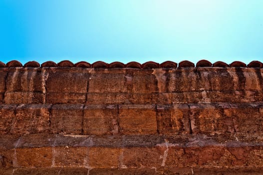 A fragment of an old weathered fence with a tiled cover.