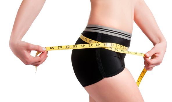 Woman measuring her waist with a yellow measuring tape