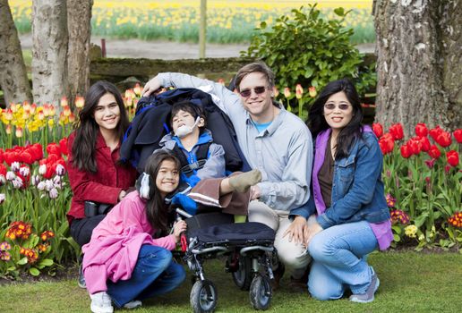 Interracial family in tulip gardens sitting near disabled boy in wheelchair. “Courtesy of RoozenGaarde (Tulips.com).”