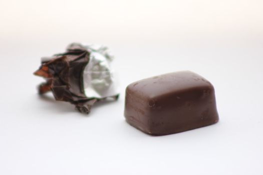Piece of chocolate candy with wrapper in background.