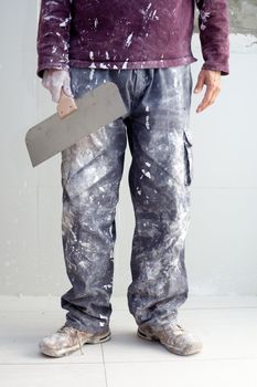 construction plastering man dirty trousers with trowel in hand
