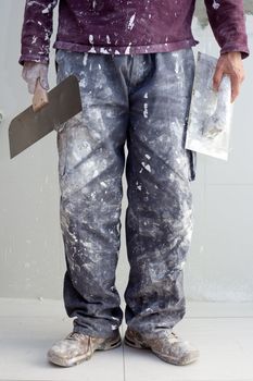 construction plastering man dirty trousers with trowel in hand