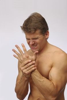 Athletic topless man holds his hand in excruciating pain
