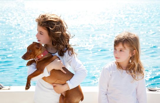 sister kid girls with dog mini pinscher on the sea view from a boat