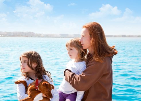 mother and daughter sister girls with dog on the sea sailing in a boat