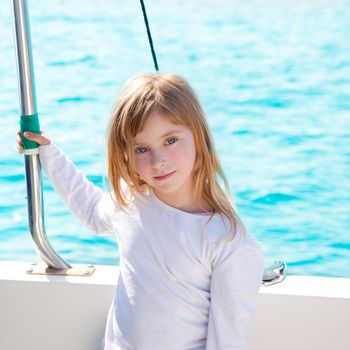 blond little kid girl sailing in a boat smiling at the sea