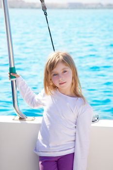 blond little kid girl sailing in a boat smiling at the sea