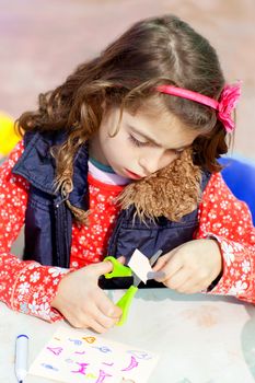 little kid girl working at school doing art work workshop cutting with scissors