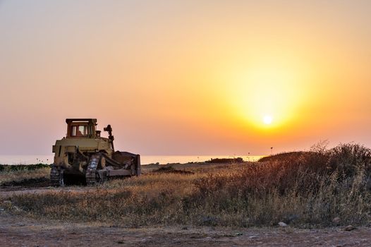 Bulldozer on the beach at sunset