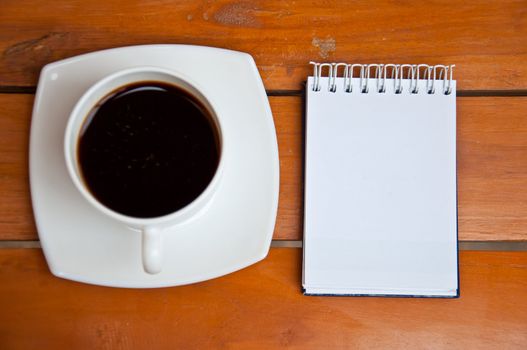 blank paper and black coffee on wood background