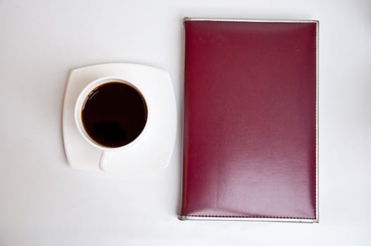 brown notebook and black coffee on white background