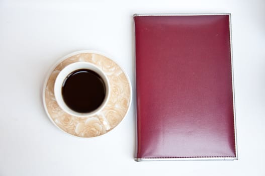 brown notebook and black coffee on white background