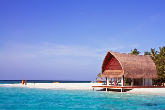 Landscape photo of beach house in Maldive ocean with blue sky