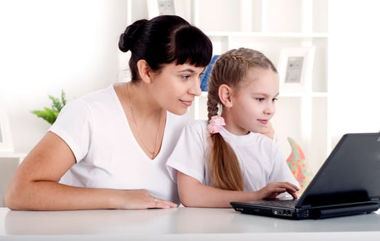 Mom and daughter are working together for a laptop at home