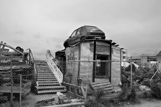 Rusty car and scrap metal at a junkyard. Black and white.