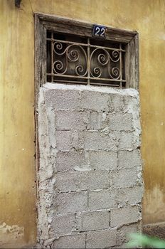 Vintage door with decorative metal swirl pattern blocked by concrete blocks.