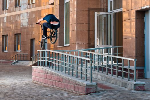 Biker doing high rail hop trick on bmx, back view