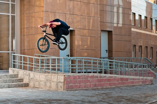 Biker doing high rail hop trick on bmx, front view