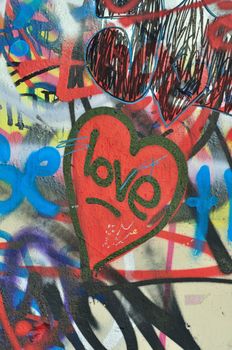 Dirty love graffiti over messy tagged urban wall background. Heart of the city.