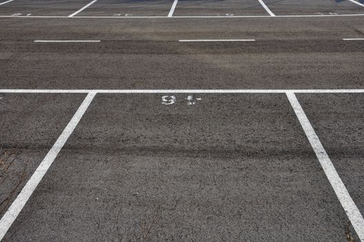 Dividing lines in empty asphalt paved parking lot abstract background.