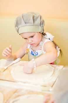 Little girl continue cooking pizza and working with dough