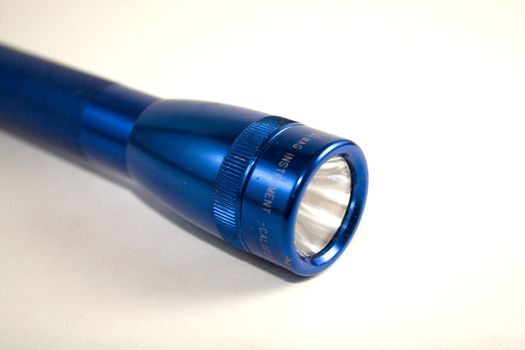Close up of blue mini flashlight on white background.
