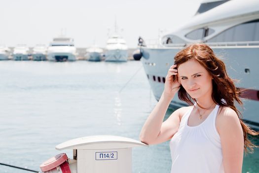 Photo of a young and beautiful girl against the backdrop of yachts in the port
