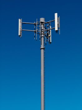 Metal tower with antennas for mobile cell phone telecommunications against blue sky with copyspace